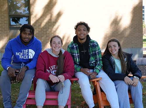 Students sitting on bench outside building